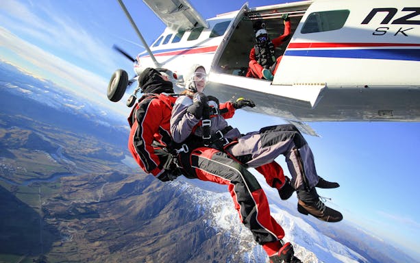 Tandem skydive over Queenstown with snowy mountains and valleys below.