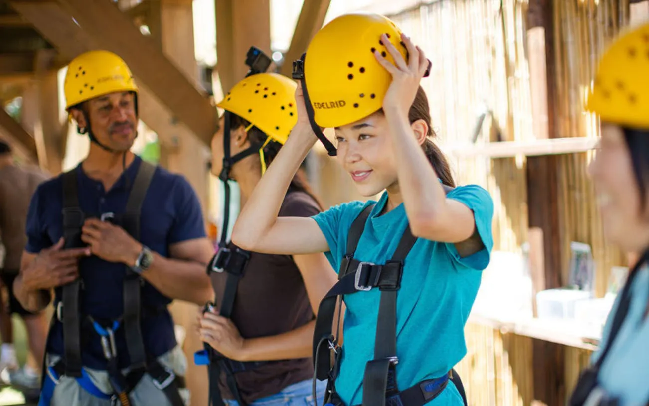 Participants preparing for a zipline adventure with helmets and harnesses.