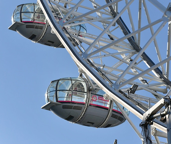 Ferris wheel capsules on the London Eye against a clear blue sky.