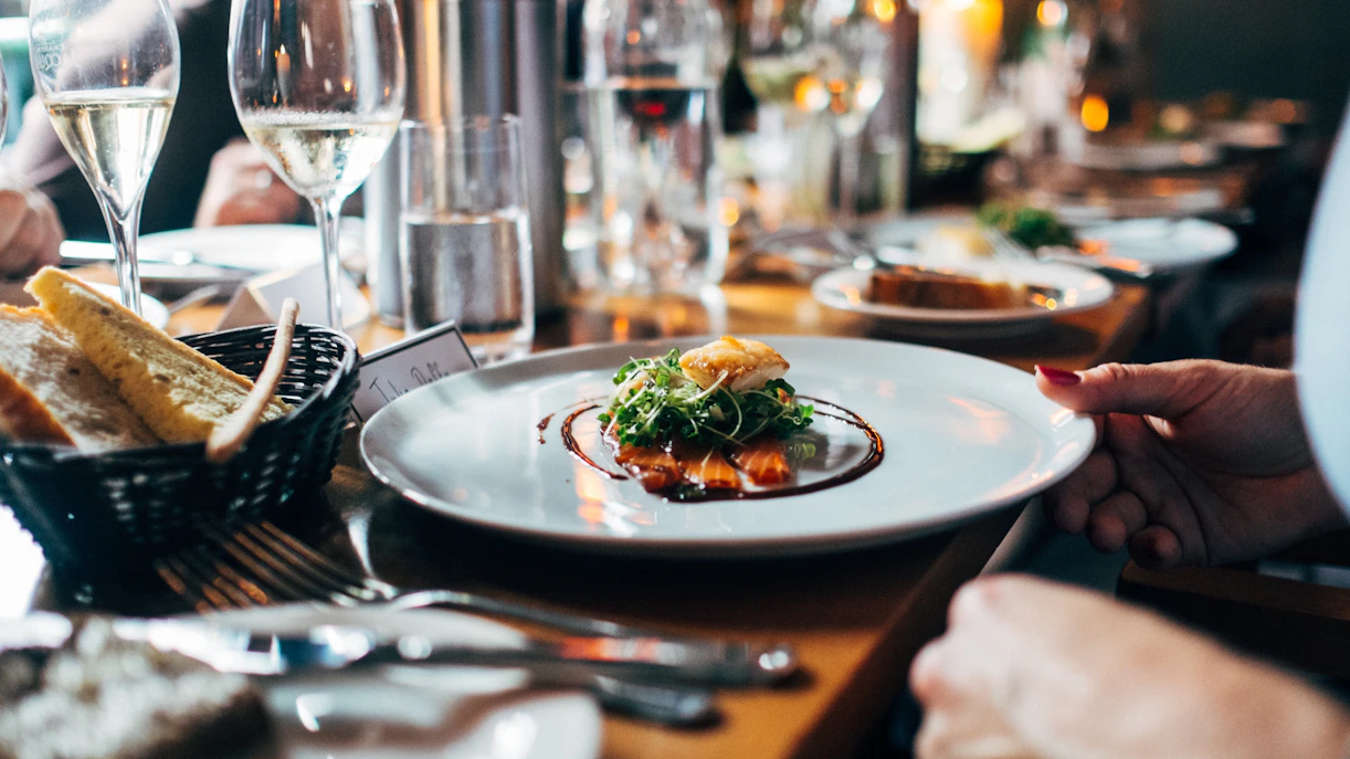 Plate of gourmet food with greens and sauce at a restaurant dinner table.