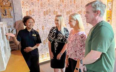 Tour guide explains an exhibit to visitors in an Egyptian-themed museum.