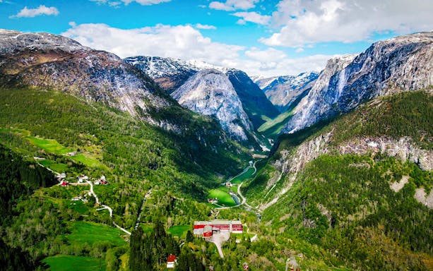 Aerial view of Flåm village nestled in a lush valley surrounded by mountains in Western Norway.