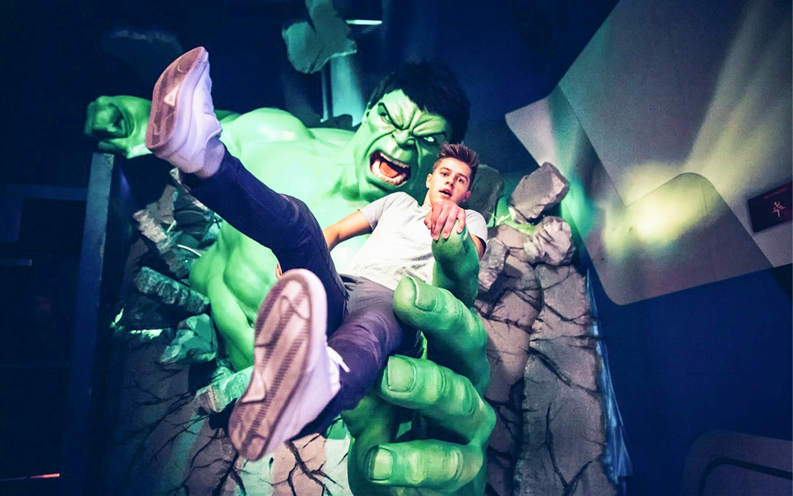 Man held by Hulk statue at Madame Tussauds, New York, experiencing 4D visuals and thrills.