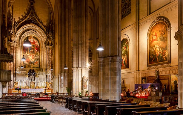 Interior of Minoritenkirche with ornate altar and classical paintings, Vienna concert venue.