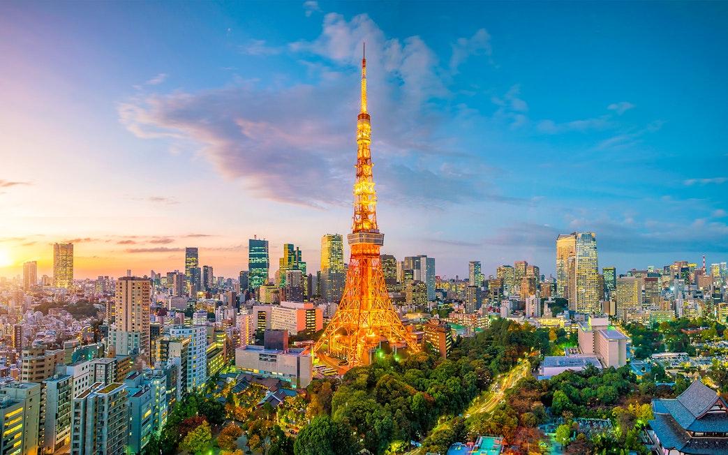 Tokyo Tower illuminated at sunset with city skyline in the background.