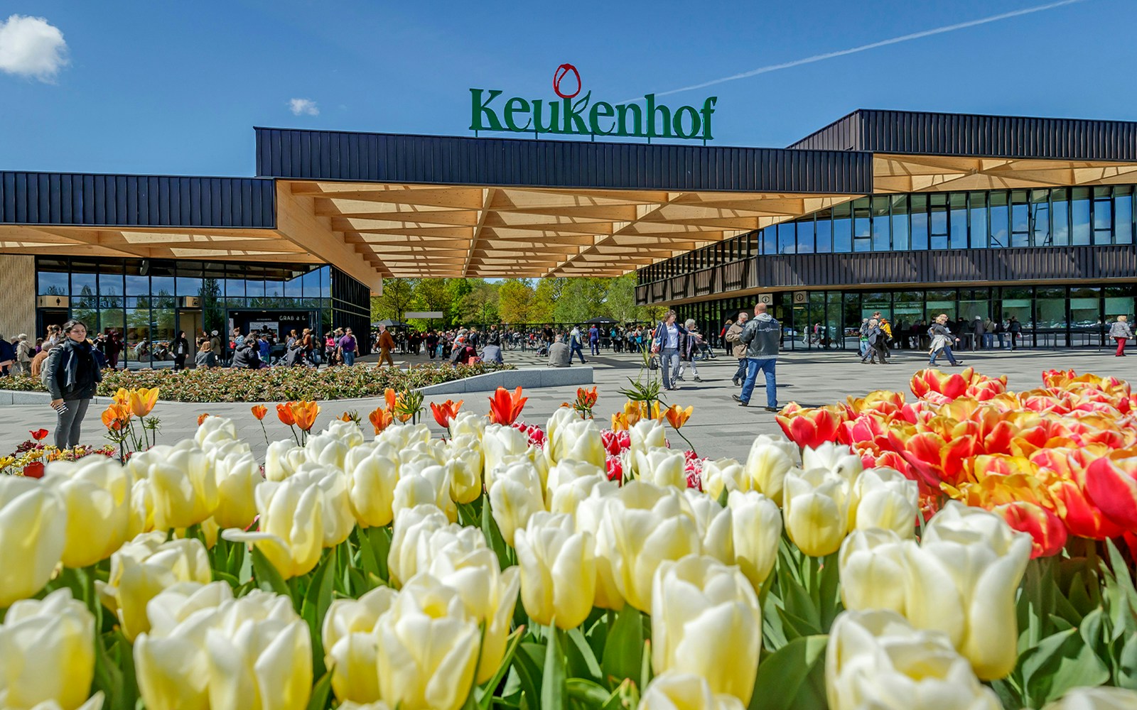 Keukenhof entrance with colorful tulips and visitors, Amsterdam tour.