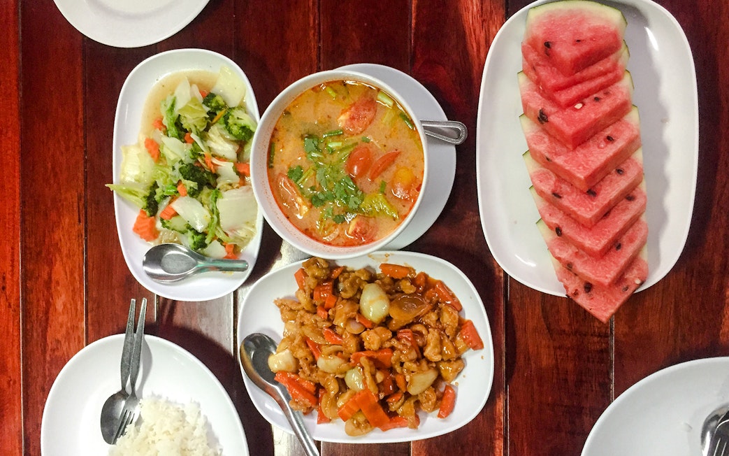 Traditional Thai food platter with curry, stir-fried vegetables, and watermelon slices in Krabi.