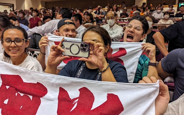 Spectators holding banners at Tokyo Grand Sumo Tournament.