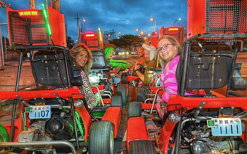 People in costumes driving go-karts on a street in Okinawa.