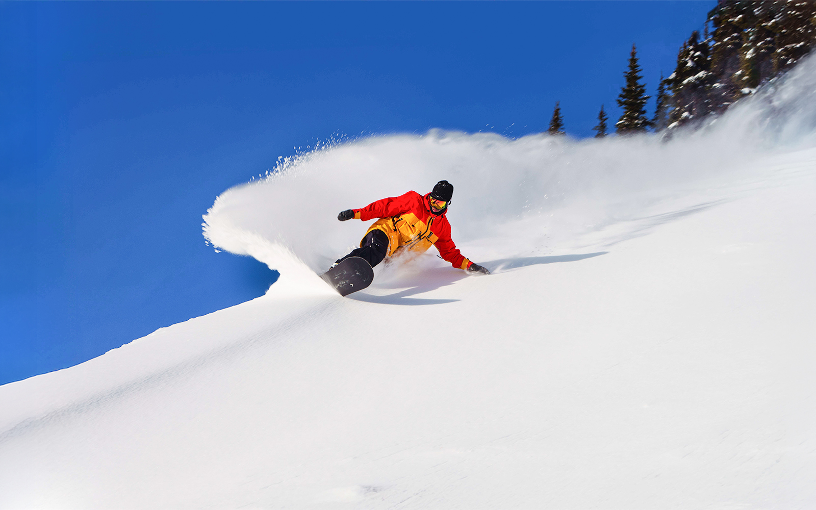 Snowboarder carving down a snowy slope with Ikon Pass, global ski pass.