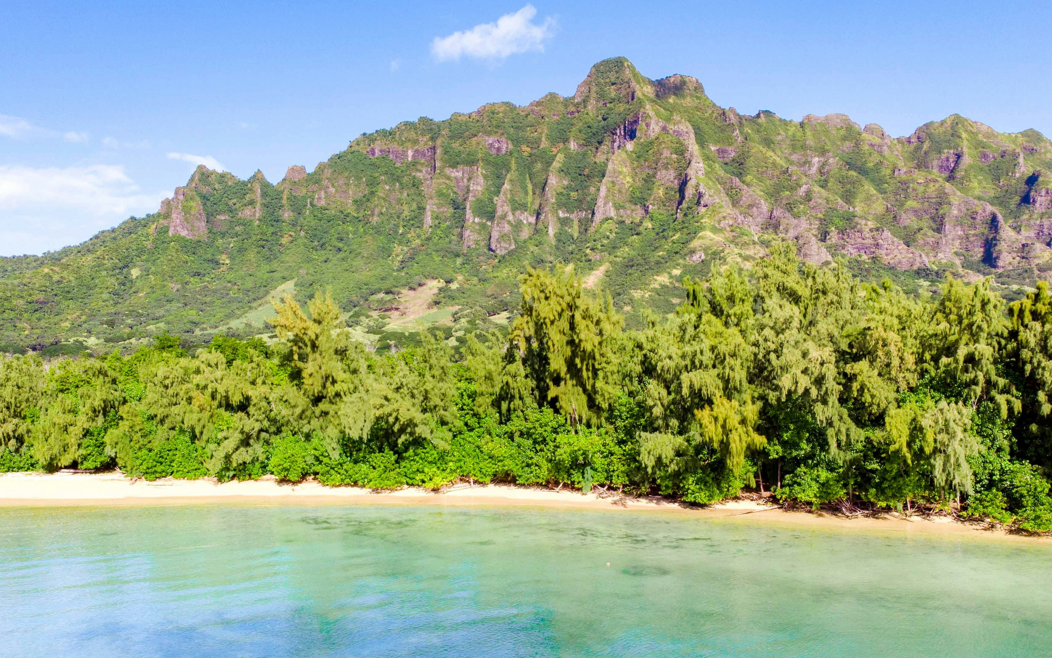 Secret Island Beach with lush greenery and mountain backdrop at Kualoa Ranch, Hawaii.