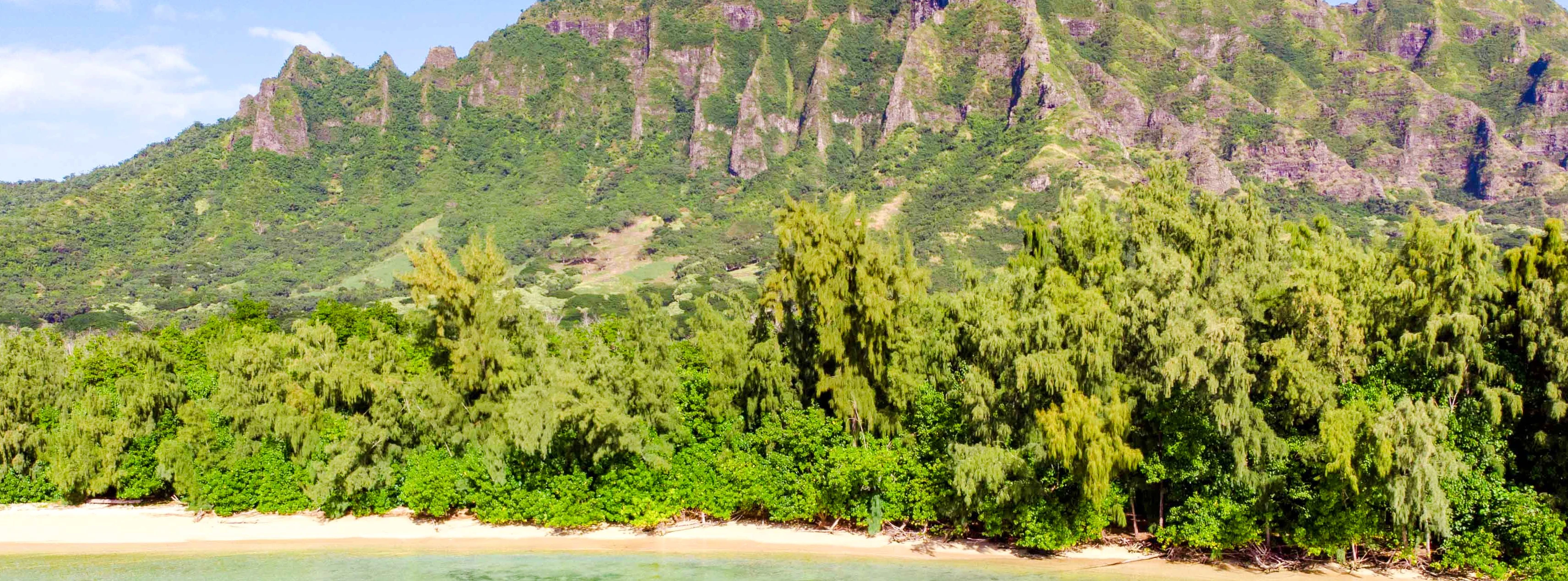 Secret Island Beach with lush greenery and mountain backdrop at Kualoa Ranch, Hawaii.