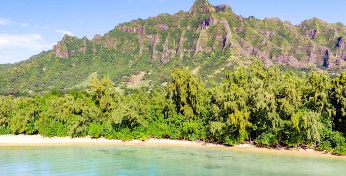Secret Island Beach with lush greenery and mountain backdrop at Kualoa Ranch, Hawaii.