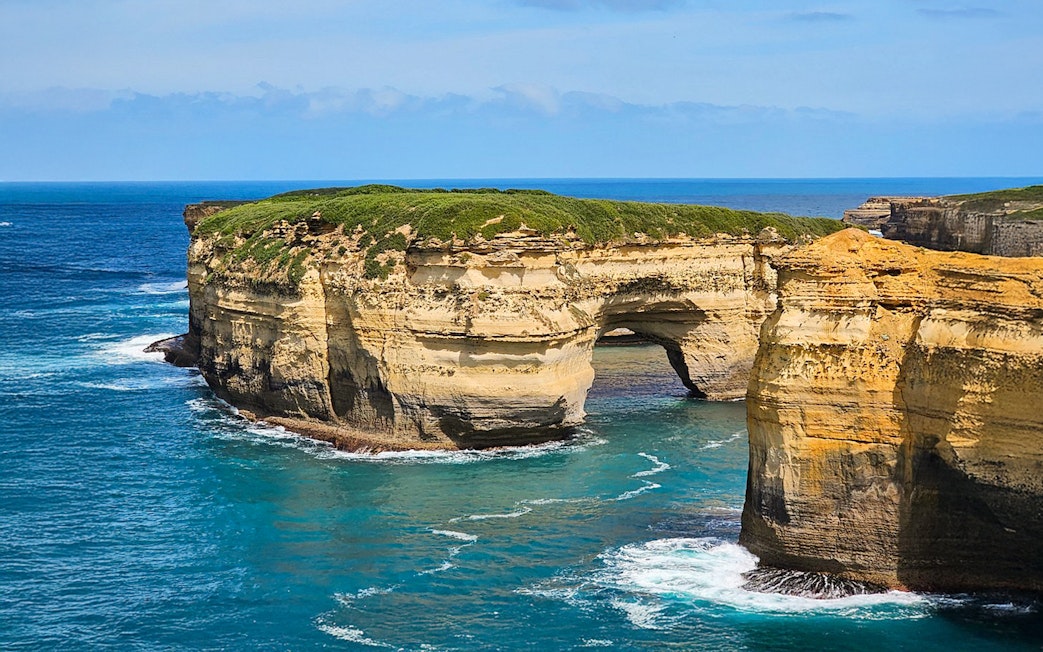 Rock formations along the Great Ocean Road coast with arch and cliffs.