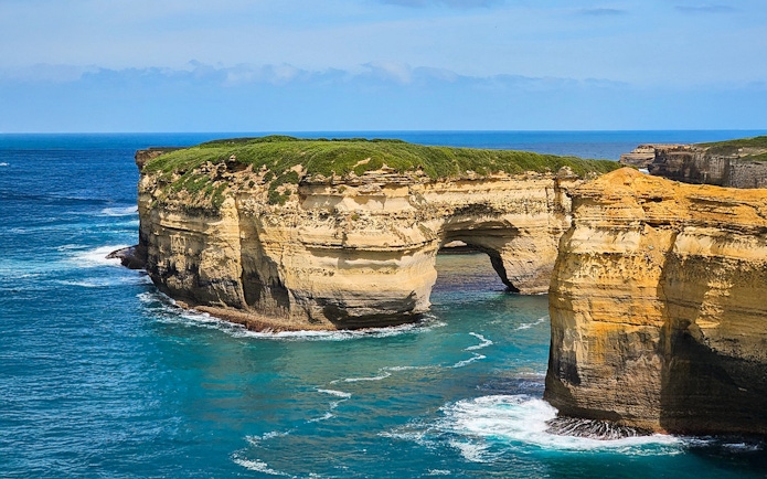 Rock formations along the Great Ocean Road coast with arch and cliffs.