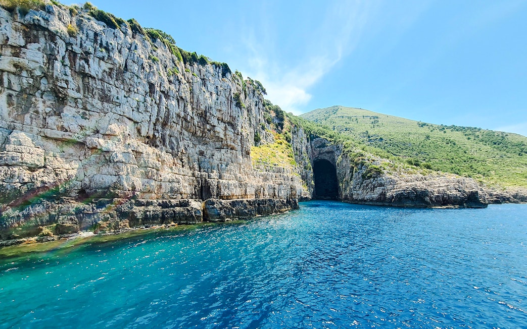 Haxhi Ali Cave entrance with clear blue water, Blue Caves Albania tour.