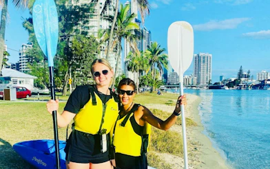 Surfers Paradise kayakers on Gold Coast beach with city skyline in background.
