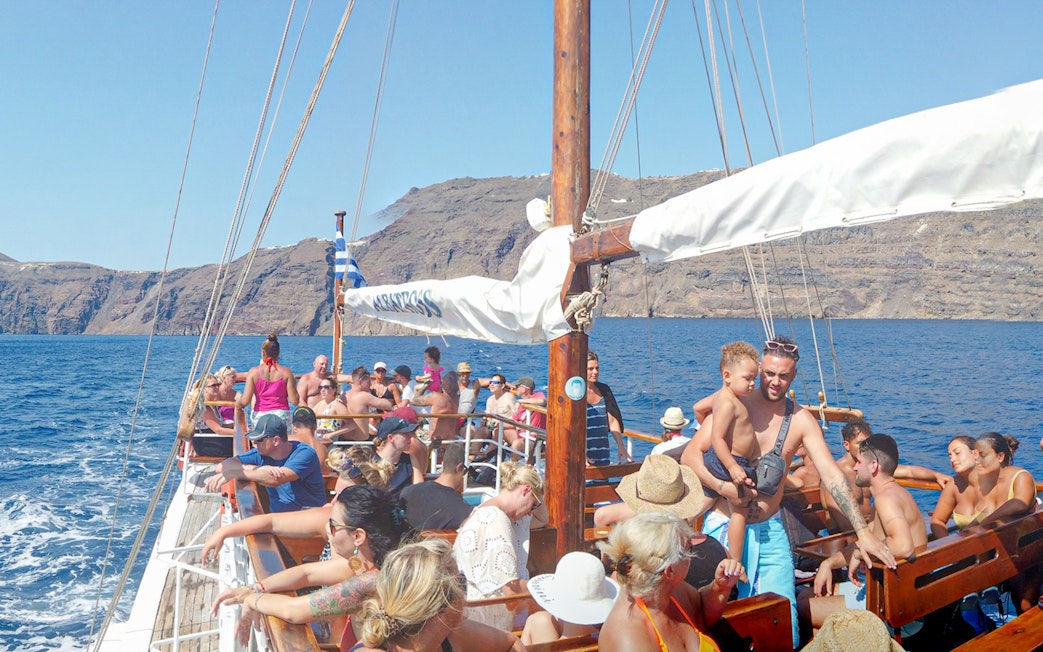 Guests on a boat enjoying Santorini Volcanic Islands cruise with scenic views.