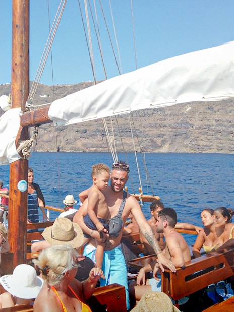 Guests on a boat enjoying Santorini Volcanic Islands cruise with scenic views.