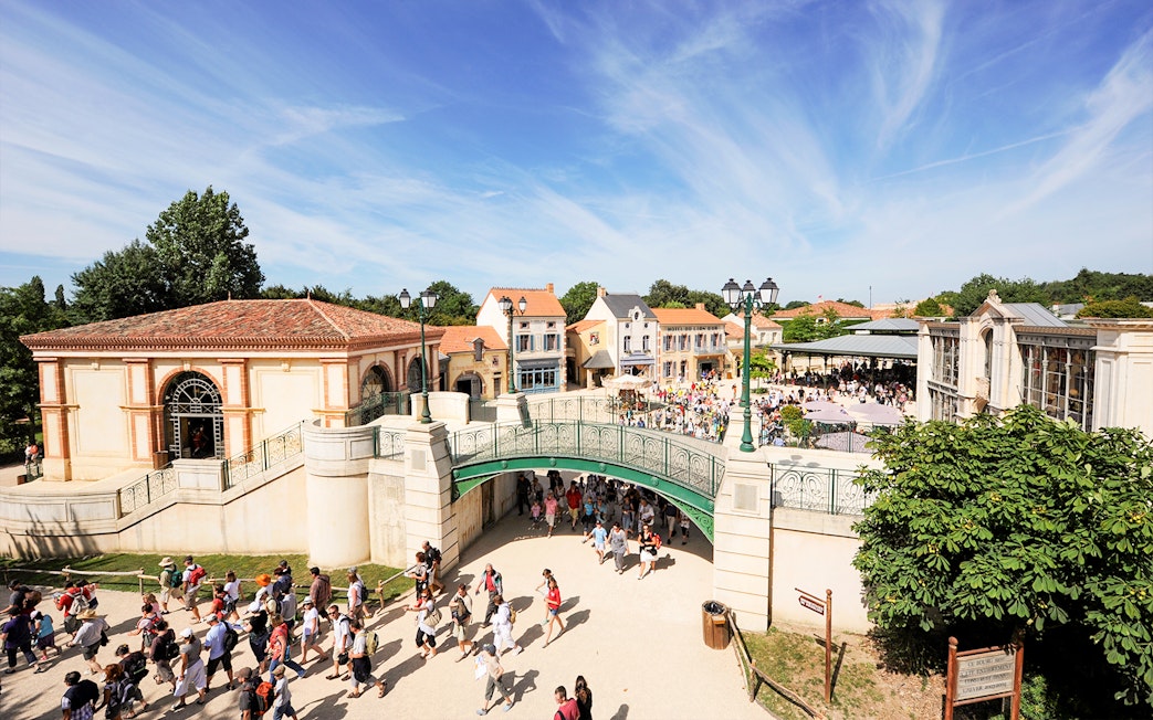 Visitors walking through Puy du Fou theme park entrance in France.