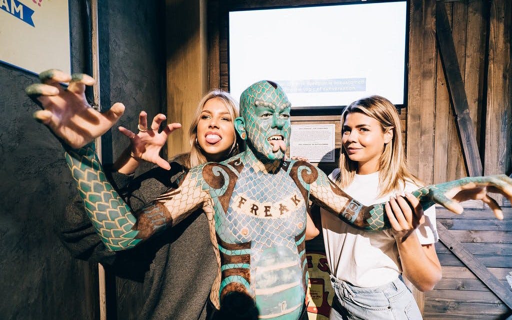 Visitors posing with a uniquely tattooed performer at Ripley's Believe It or Not! exhibit.