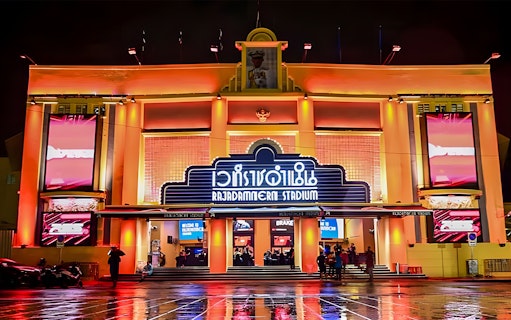 Rajadamnern Boxing Stadium exterior illuminated at night, Bangkok, Thailand.