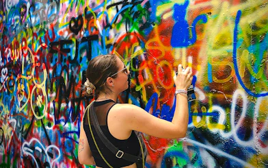 Guest spray painting colorful graffiti on a wall during Medellin Comuna tour.
