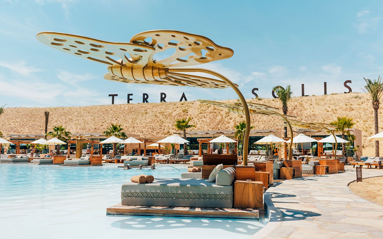Poolside lounge area at Terra Solis with sunbeds and umbrellas.
