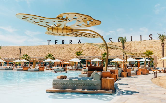 Poolside lounge area at Terra Solis with sunbeds and umbrellas.