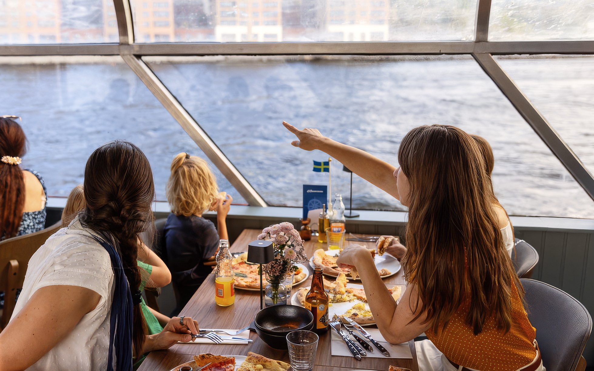 Guests enjoying pizza on a Stockholm cruise with a view of the water.