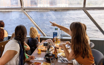 Guests enjoying pizza on a Stockholm cruise with a view of the water.