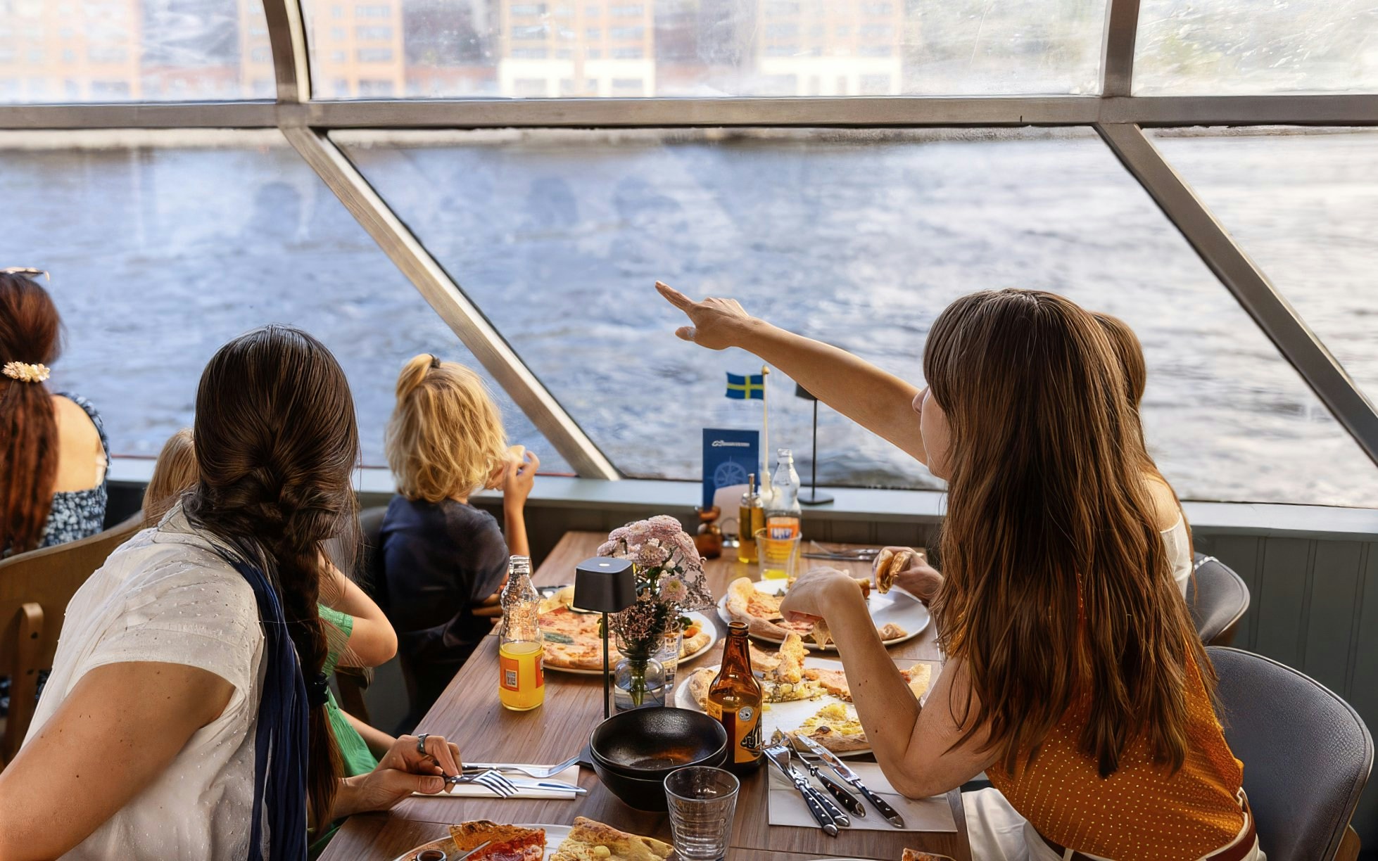 Guests enjoying pizza on a Stockholm cruise with a view of the water.
