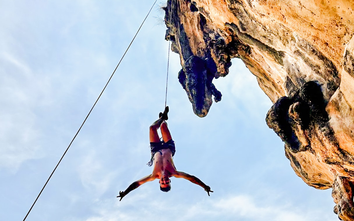 Climber suspended on a rope at Krabi Rock Climbing Courses, Railay, Thailand.