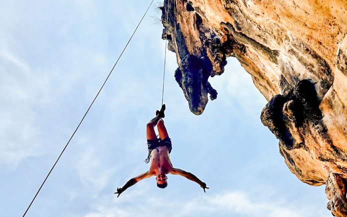 Climber suspended on a rope at Krabi Rock Climbing Courses, Railay, Thailand.