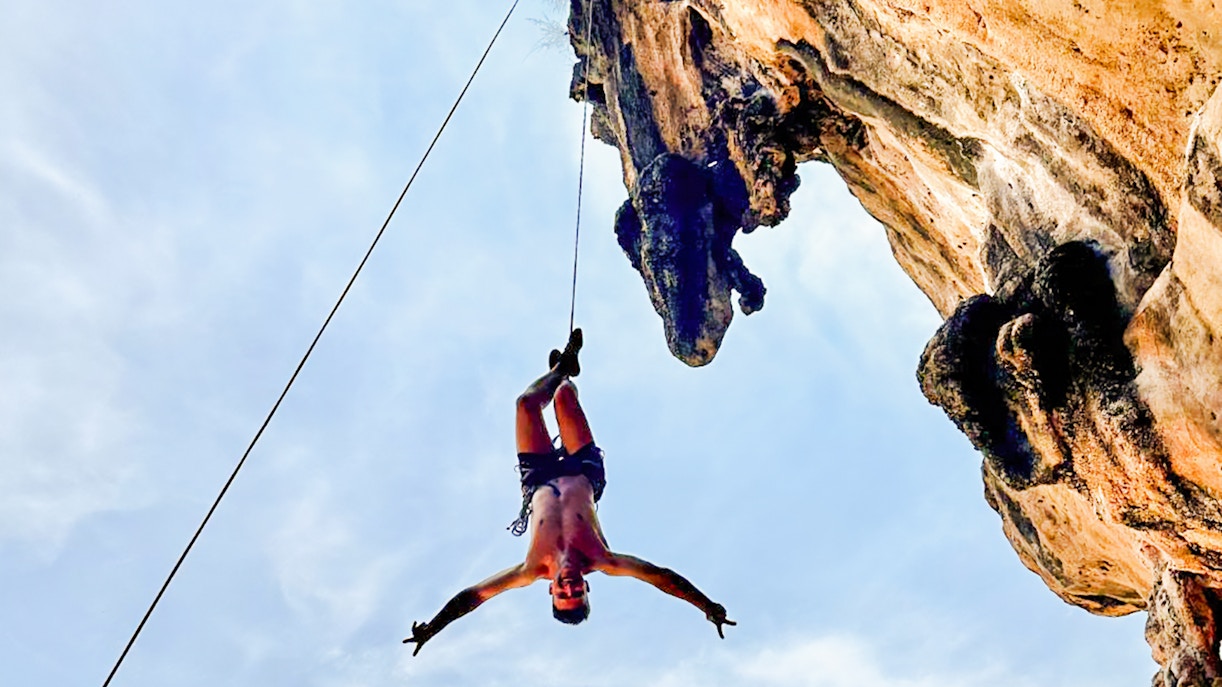 Climber suspended on a rope at Krabi Rock Climbing Courses, Railay, Thailand.