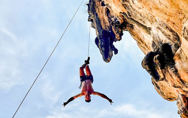 Climber suspended on a rope at Krabi Rock Climbing Courses, Railay, Thailand.