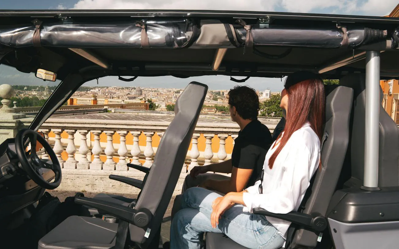 Tourists enjoying a panoramic view of Rome from a golf cart.