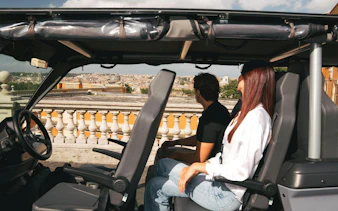 Tourists enjoying a panoramic view of Rome from a golf cart.
