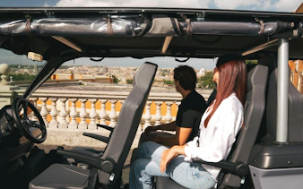 Tourists enjoying a panoramic view of Rome from a golf cart.
