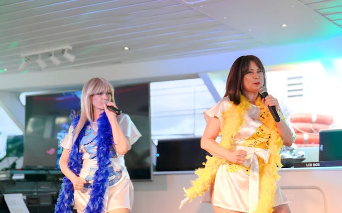Abba tribute performers singing on a Sydney cruise stage.