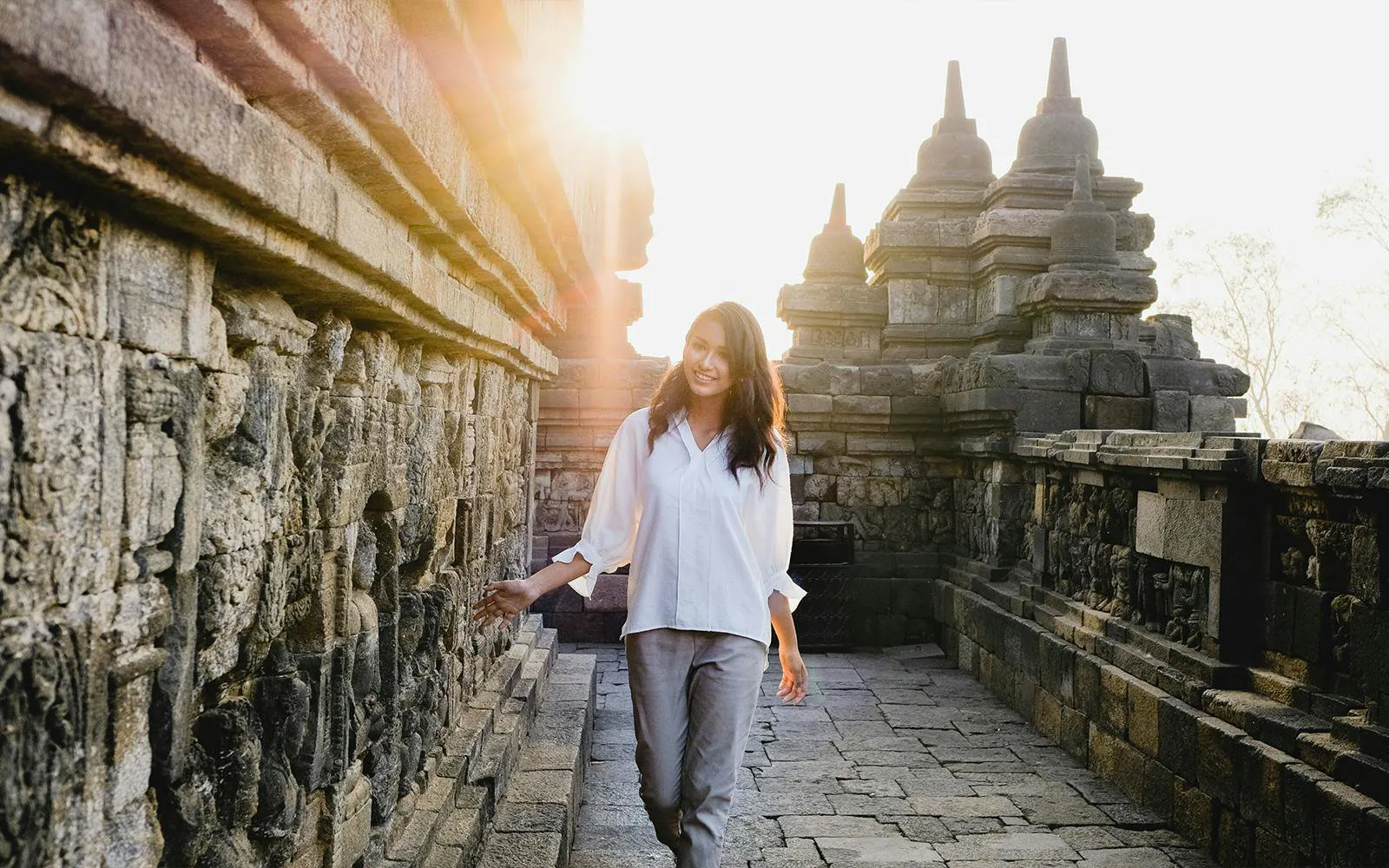 Woman exploring ancient Borobudur temple in Indonesia at sunrise.