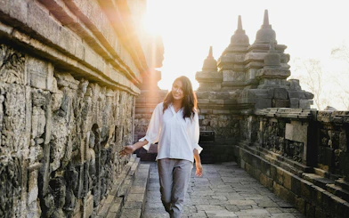 Woman exploring ancient Borobudur temple in Indonesia at sunrise.