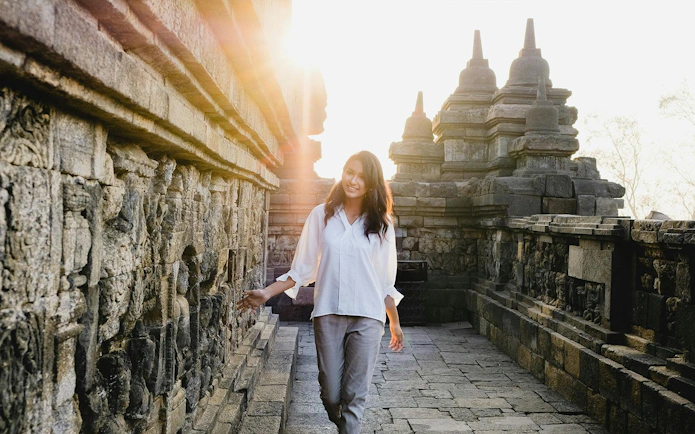 Woman exploring ancient Borobudur temple in Indonesia at sunrise.