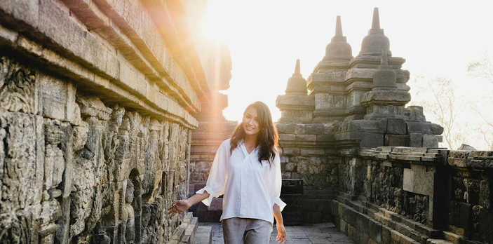 Woman exploring ancient Borobudur temple in Indonesia at sunrise.