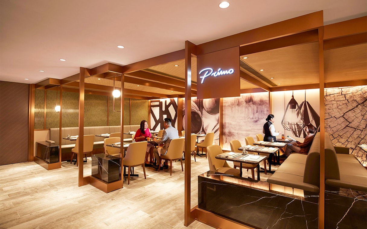 First-class lounge seating area at Hong Kong International Airport with guests dining.