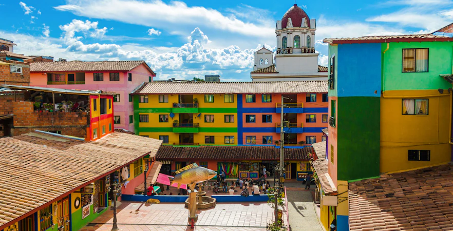 Colorful buildings and plaza with a fish sculpture in Guatape, Colombia.