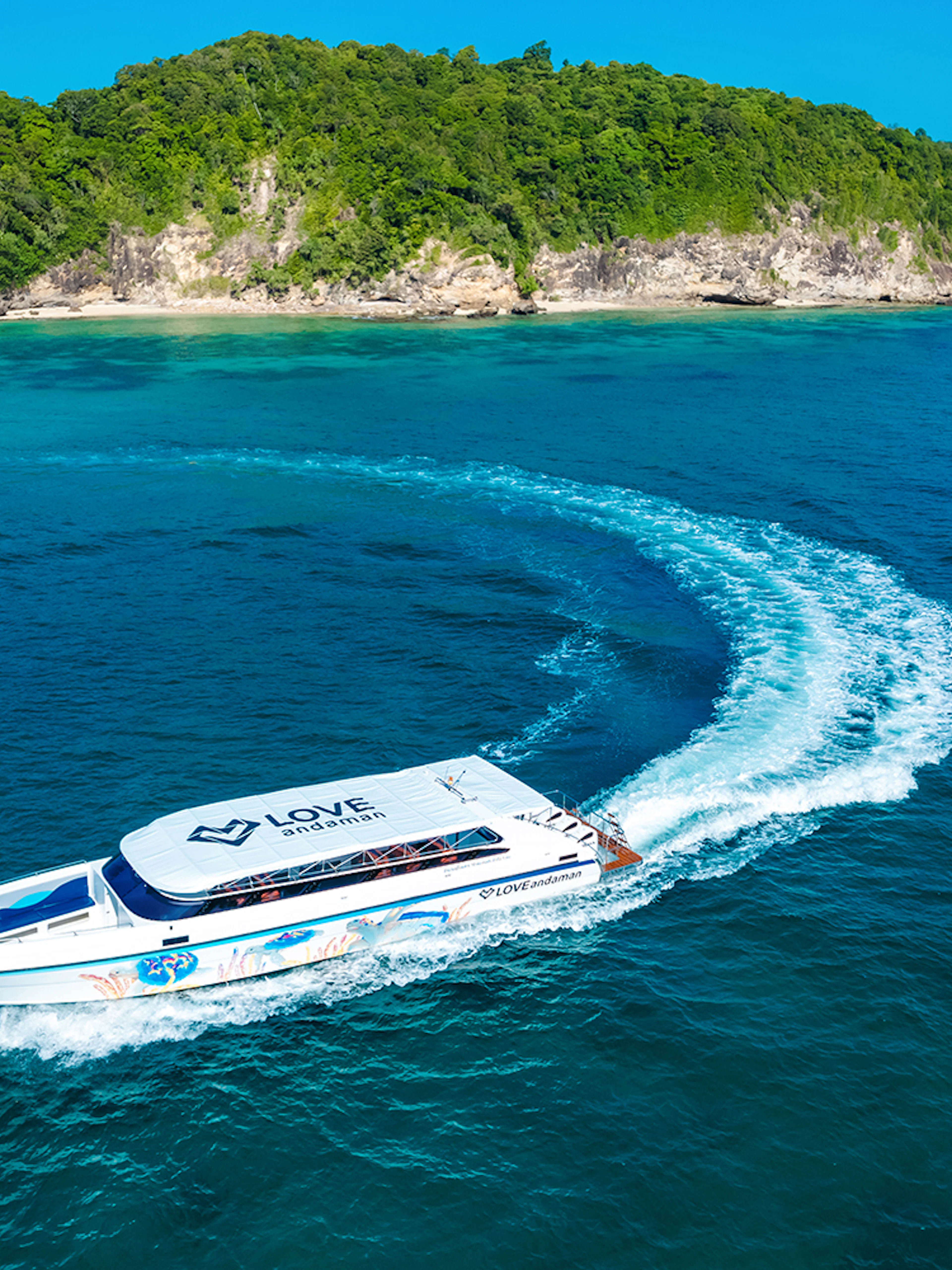 Speed boat cruising towards Similan Island with lush green coastline in the background.
