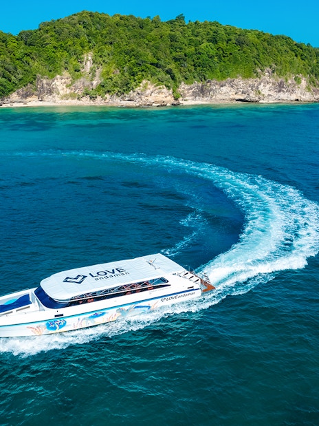 Speed boat cruising towards Similan Island with lush green coastline in the background.
