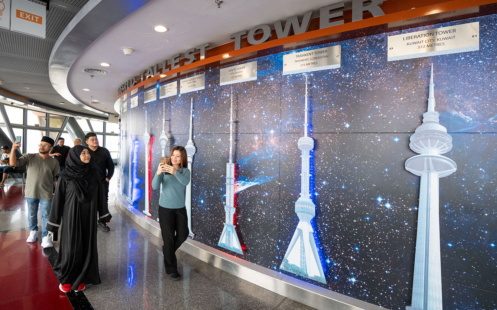 Tourists at Kuala Lumpur Tower Observation Deck viewing tower models display.