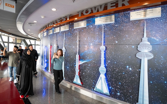 Tourists at Kuala Lumpur Tower Observation Deck viewing tower models display.